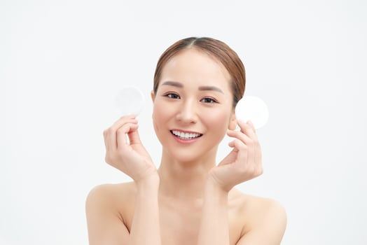 Smiling woman holds cotton pads on white background. Skin care concept. photo
