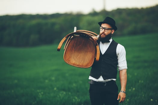 Bearded man carries a chair on the field photo