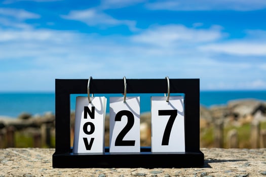 Nov 27 calendar date text on wooden frame with blurred background of ocean. photo