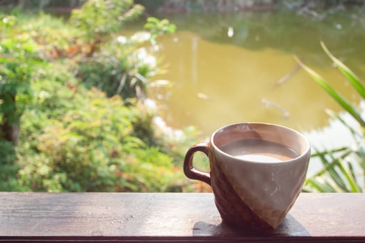 A cup of hot cocoa by the wooden balcony on nature background for the new morning. photo