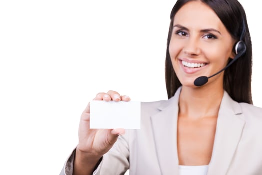 Call this number Beautiful young businesswoman in headset showing her business card and smiling while isolated on white background photo