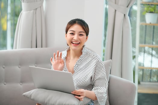 Cheerful pretty lady using laptop to chat with friend online stock photo