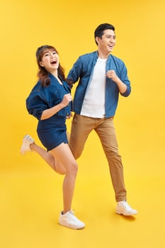 Attractive smiling young Asian couple being happy and amazed isolated on yellow studio background photo