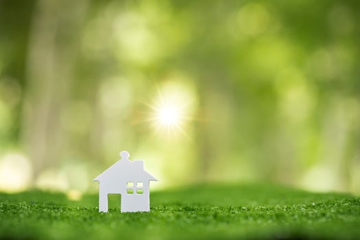 Environmentally eco-friendly real estate house. Small model building property home on grass in green nature ecology. Sustainable energy conservation residential design and sell - rent business concept photo