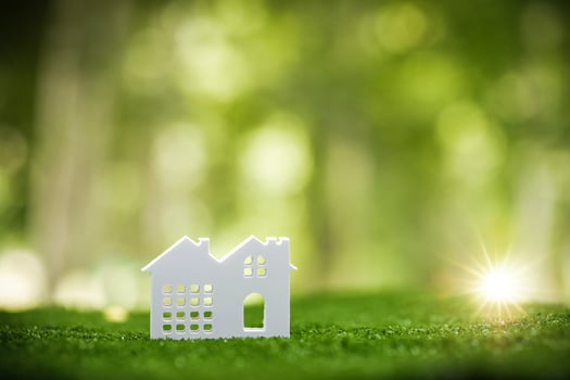 Environmentally eco-friendly real estate house. Small model building property home on grass in green nature ecology. Sustainable energy conservation residential design and sell - rent business concept photo