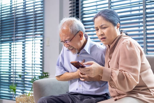 Asian senior man is suffering from heart attack while his wife is searching for paramedic doctor and ambulance rescue team for emergency situation concept photo