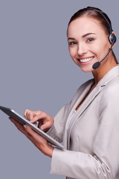 Beauty at work. Side view of Confident young female operator holding digital tablet while standing against grey background photo