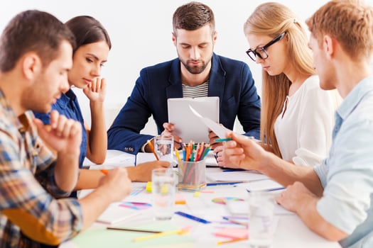 Concentrated on work. Group of confident business people in smart casual wear working together while sitting at the table photo