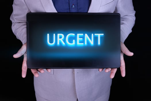 URGENT word, text written in neon letters on a laptop which is being held by a businessman in a gray suit. photo