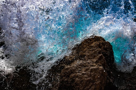 Turquoise waves of sea water break and spray drops on stones. Close-up. Red sea photo