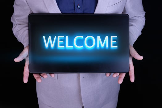 WELCOME text, word written in neon letters on a black laptop, in front of a businessman in a gray suit. photo