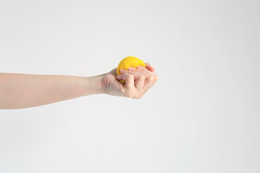 Hand pressing yellow squishy ball for exercise muscle or for feeling relax from stress in concept of health care and medical. photo