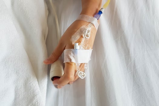 Close-up of patient hand with infusion needle and IV tube for intravenous infusion pushing emergency button at bed. photo