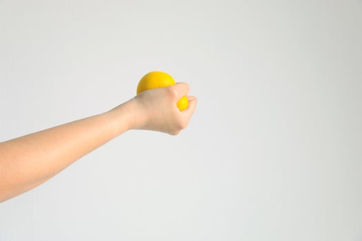 Hand pressing yellow squishy ball for exercise muscle or for feeling relax from stress, concept of health care and medical. photo