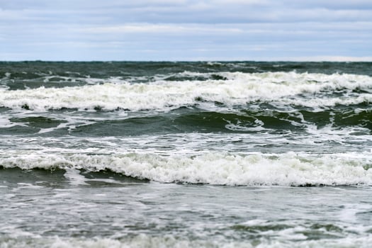Blue sea with foaming waves and cloudy sky, seascape photo