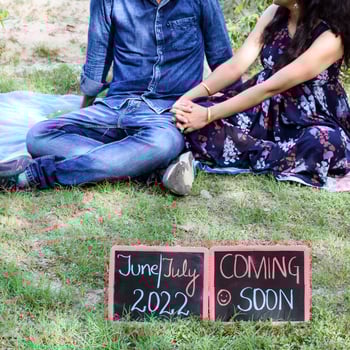Indian couple posing for maternity baby shoot. The couple is posing in a lawn with green grass and the woman is falunting her baby bump in Lodhi Garden in New Delhi, India photo