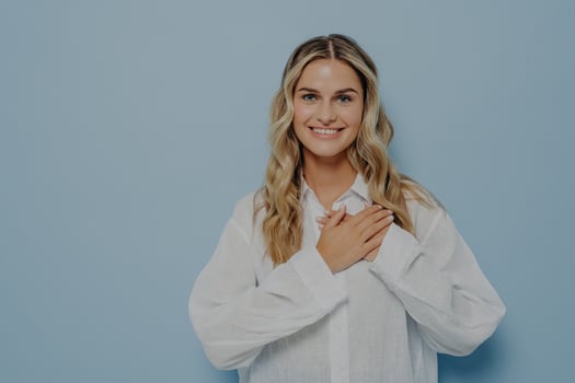 Relieved blonde woman with hands on her chest photo