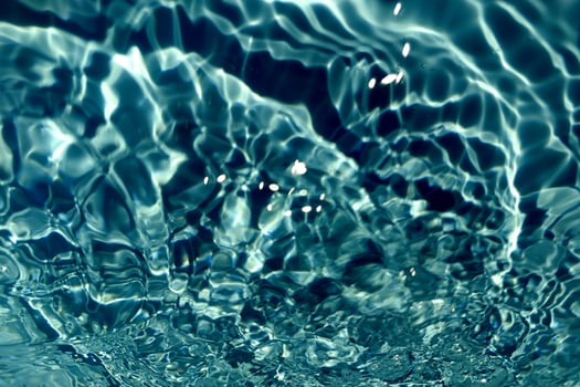 Defocus blurred transparent blue colored clear calm water surface texture with splashes and bubble. Trendy abstract nature background. Water wave in sunlight with copy space. Blue watercolor shining. photo