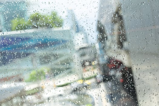 Morning city,view through the window on rainy day. Water droplets on the glass on a rainy day. rain drops during raining in rainy day outside window glass with blurred background. photo