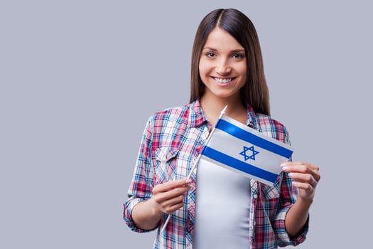 Beauty with Israeli flag. Happy young women holding flag of Israel while standing against grey background photo