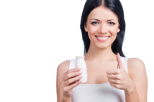 If you want to be healthy choose it Beautiful young smiling woman holding a bottle and gesturing while standing against white background photo