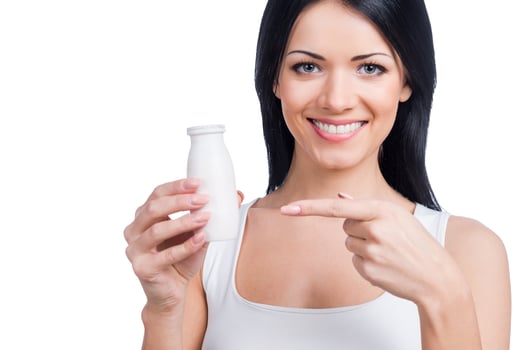 Beverage of health. Beautiful young smiling woman holding a bottle and pointing on it while standing against white background photo