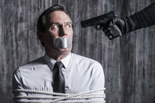 Please no. Tied up businessman with adhesive tape on his mouth sitting in front of the dirty wall while someone aiming his head photo