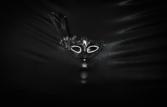 Fancy party mask with screaming human face press through black fabric for Halloween background concept. photo
