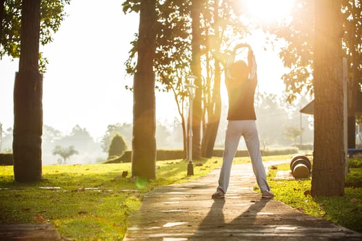 Asian woman jogging in park with cloudy sky and lens flare photo