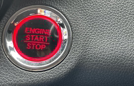 car engine start stop button on dark leather background. copy space photo