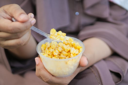 women holding a plastic bowl of organic sweet corn photo