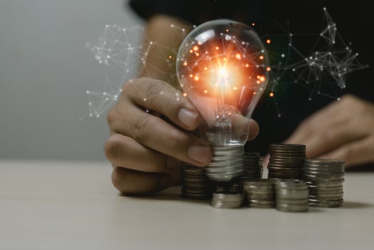 Innovation creativity growth idea success economy development strategy business concept.Hand holding light bulb on coin stack saving money on desk. photo