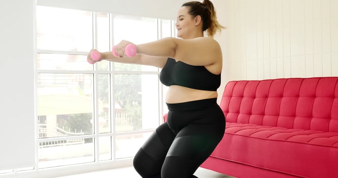 Chubby woman doing exercise by dumbbell in a room. photo