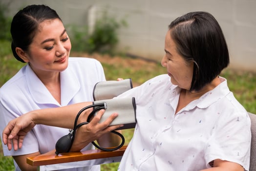 Beautiful nurse doing pressure measuring for female patient at the hospital park. photo