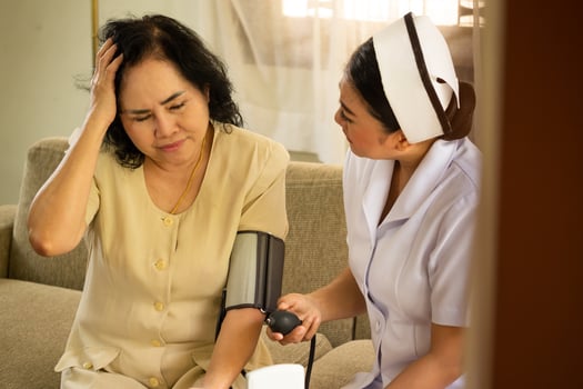 Asian nurse doing pressure measuring for female patient who hasing headache in the room. photo
