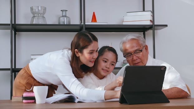 Grandfather and mother are teaching daughter homework while studying online at home. photo