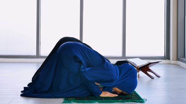 Two Asian Muslim young women in traditional hijab are praying glorify Allah and practicing the Islamic faith in mosque. photo