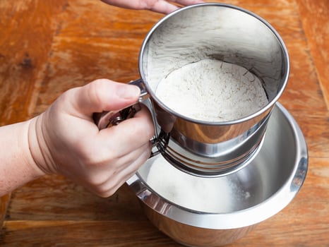 sifting the wheat flour through sifter into bowl photo