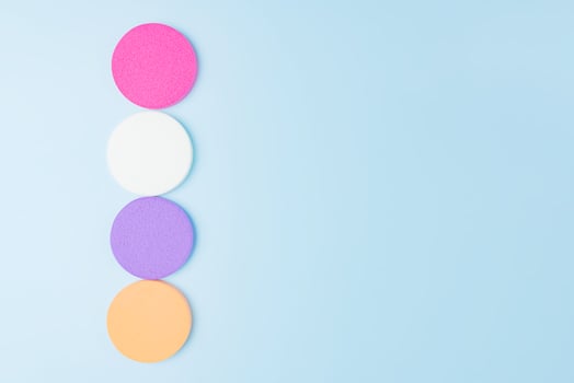 Multicolor cosmetic makeup sponge set on blue background. A set of sponges of round shape. Tool for applying foundation cream. photo