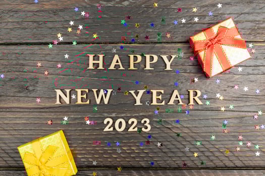 Happy new year 2023 next and red and yellow small gift boxes on dark wooden background with confetti. photo