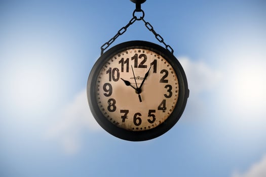 Closeup vintage hanging clock, blurred clouds and bluesky background. photo