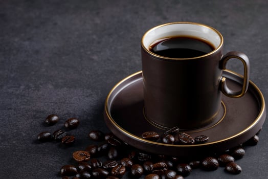 Coffee is hot in a brown coffee cup and coffee beans are placed a little. Warm and light atmosphere on a dark background with photocopying area. photo