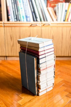 stack of old book tied with twine on wooden floor photo