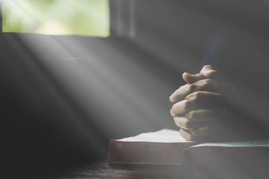 Hand folded in prayer to god on Holy Bible book in church concept for faith, spirituality and religion, woman person praying on holy bible in morning. christian catholic woman hand with Bible worship. photo