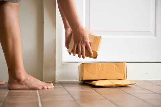 Woman collects parcel at door. box near door on floor. Online shopping, boxes delivered to your front door. Easy to steal when nobody is home. Parcel in cardboard box on doorstep. Delivery service photo