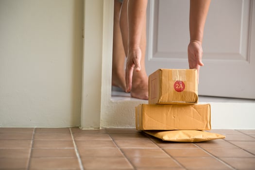 Woman collects parcel at door. box near door on floor. Online shopping, boxes delivered to your front door. Easy to steal when nobody is home. Parcel in cardboard box on doorstep. Delivery service photo