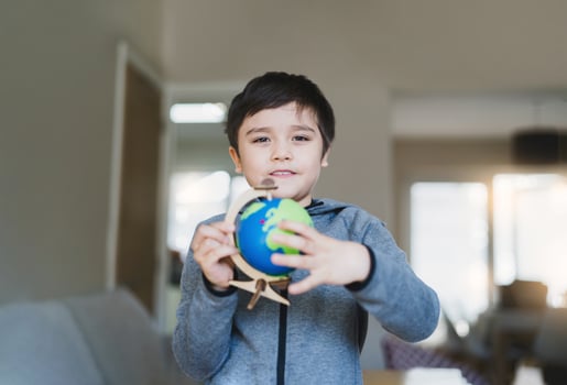 Portrait Kid is looking at a globe, School boy learning about Geography, young boy with happy face holding world map standing in living room, World Children s Day, Education and Homeschooling concept photo