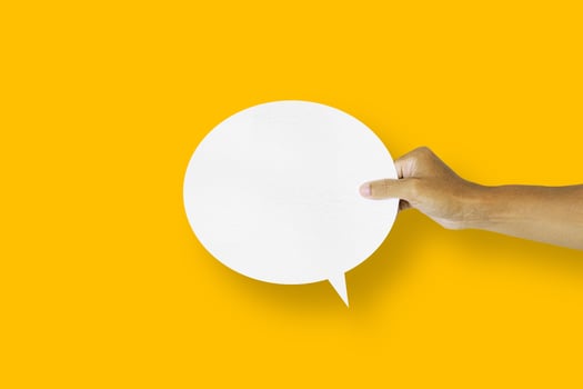 hand holding round white paper balloons speech bubbles isolated on yellow background photo
