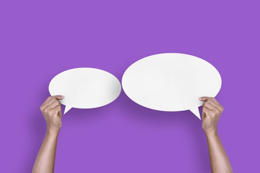 hand holding round white paper balloons speech bubbles isolated on purple background photo