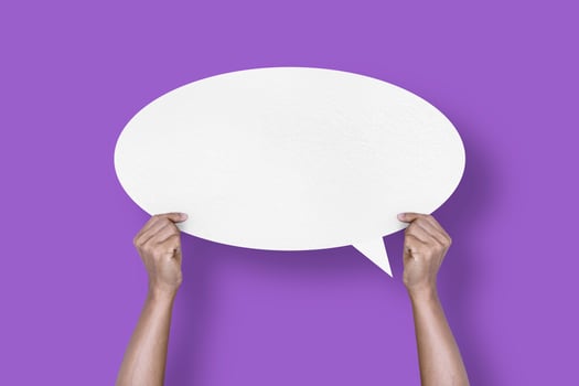 hand holding round white paper balloons speech bubbles isolated on purple background photo